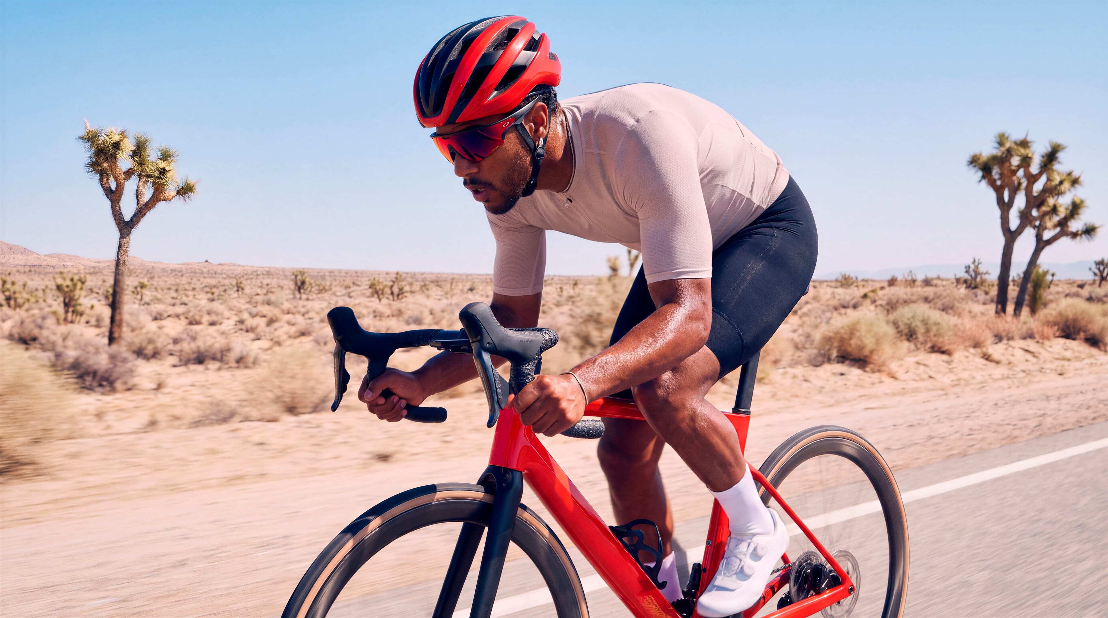 A cyclist riding hard on a desert road, wearing smart glasses.